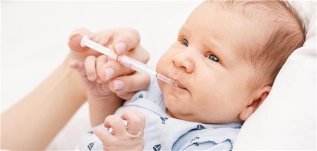 Ein Säugling bekommt oral eine flüssige Arznei verabreicht.