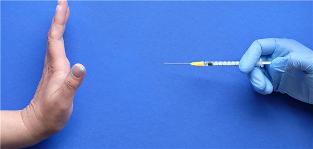 Eine Hand lehnt demonstrativ eine Spritze ab.