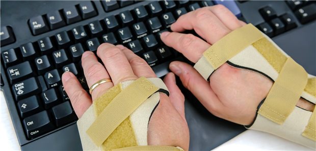 Trotz Rheuma weiter erwerbstätig bleiben können Hände in Handgelenksschienen auf der Tastatur