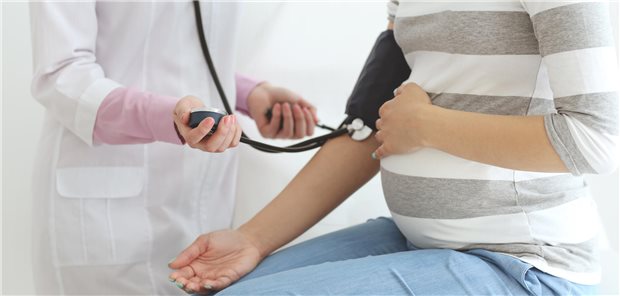 Eine schwangere Frau bekommt den Blutdruck von einer Ärztin gemessen.