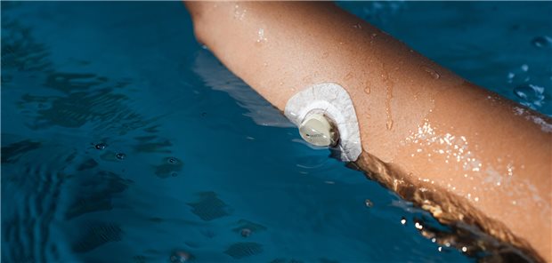 Eine Frau mit einem Gerät zur kontinuierlichen Blutzuckermessung im Schwimmbad.