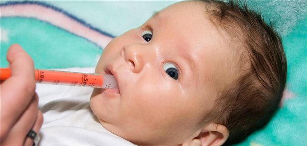 Baby kriegt Arznei per Spritze in den Mund gespritzt.