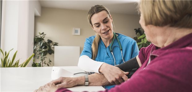 Eine MFA nimmt bei einer Patientin Blutdruck.