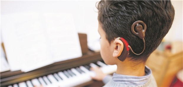 Eltern gegen Operation des gehörlosen Kindes Die Welt der Hörenden: Ein zehnjähriger Junge, der Cochlea-Implantate trägt, spielt auf einem Klavier.