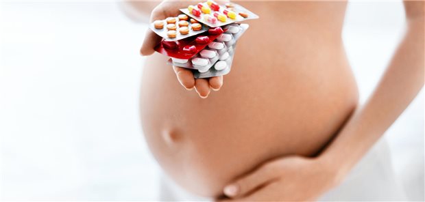 Schwangere hält Tabletten in der Hand.