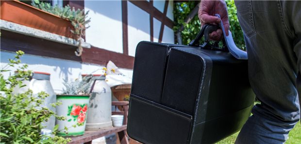 Eine Hand trägt eine Arzttasche.