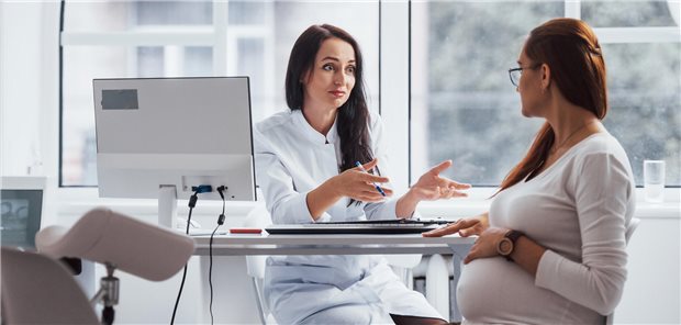 Eine schwangere Frau befindet sich in einem Konsultationsgespräch mit einer Gynäkologin.