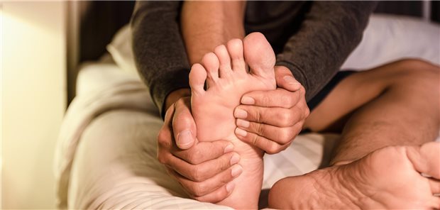 Mann hält sich Fuß fest.