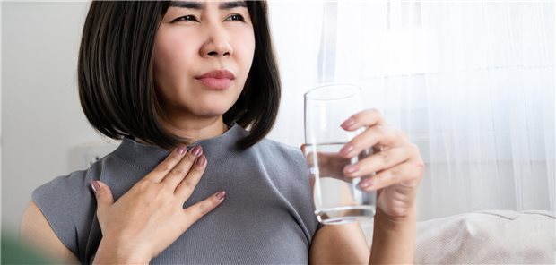 Frau leidet unter Schluckbeschwerden beim Trinken von Wasser.