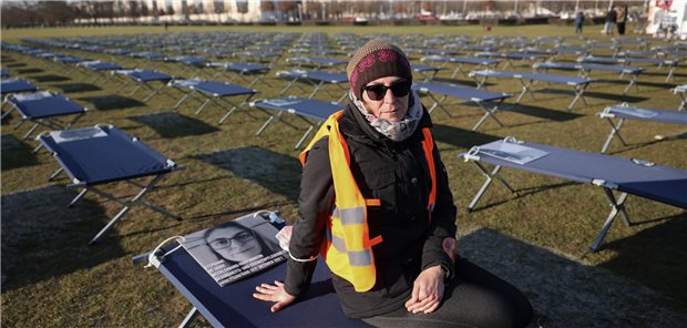 400 Betten für mehr Long-COVID-Forschung Die ehemalige Intensivkrankenschwester Stephanie sitzt als Betroffene bei einer Demonstration von Long COVID und ME/CFS-Betroffenen vor dem Reichstagsgebäude auf einem Feldbett. 400 Feldbetten mit Porträts von Betroffenen aus ganz Deutschland wurden insgesamt aufgestellt.