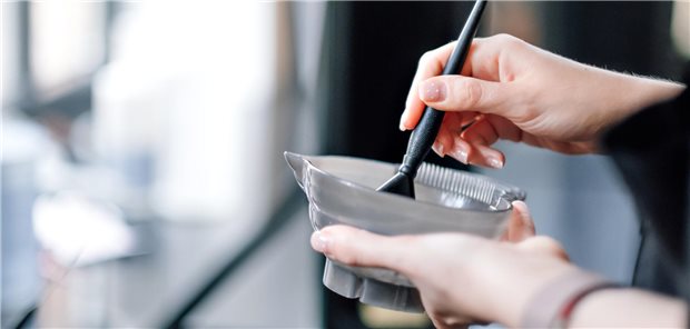 Nahaufnahme einer Friseurin, die in ihren Händen eine Schüssel mit Haarfärbemittel hält.