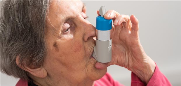 Eine ältere Frau inhaliert ein Medikament aus einem Pulverinhalator.