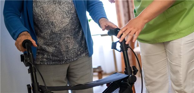 Pflegekraft mit Frau am Rollator