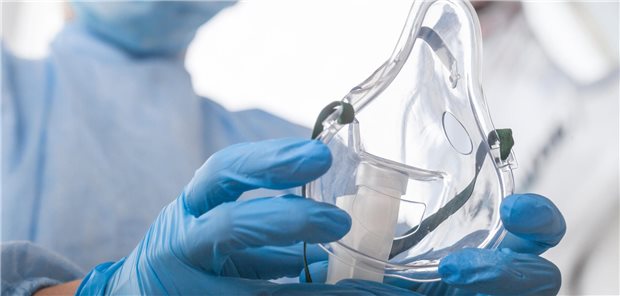 Ein Arzt in Schutzausrüstung setzt einer Patientin mit Coronavirus-Diagnose eine  Sauerstoffmaske auf.
