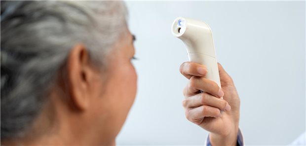 Eine Krankenschwester misst die Temperatur einer älteren Frau mit einem berührungslosen Infrarot-Thermometer.