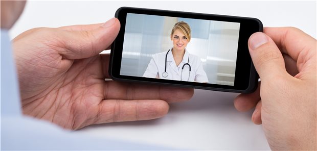 Telemedizin-Projekte in Hessen boomen Person mit einem Smartphone in der Hand, auf dem eine Ärztin zu sehen ist.