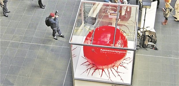 Passanten bringen überdimensionale Krebszelle zum Schrumpfen Die überdimensionale aufblasbare Krebszelle im Berliner Bahnhof.