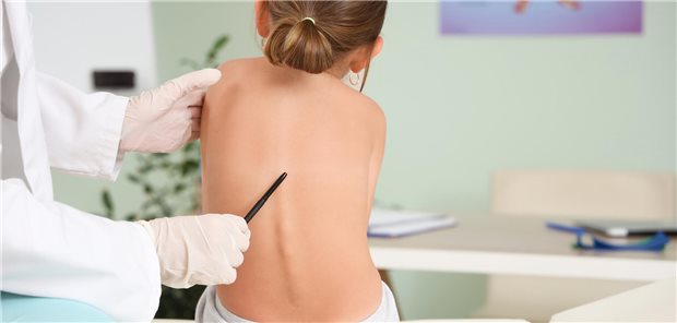 Weibliche Osteopathin arbeitet mit einem kleinen Patienten auf einer Liege in einer Klinik.