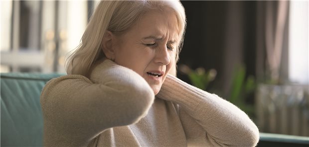 Eine Frau greift sich mit beiden Händen um den Nacken.