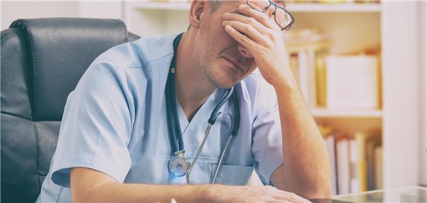 Erschöpfter Arzt hält sich die Hand vor die Augen