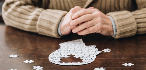 Ein Mann puzzelt ein Puzzle, das aussieht wie ein Schädel