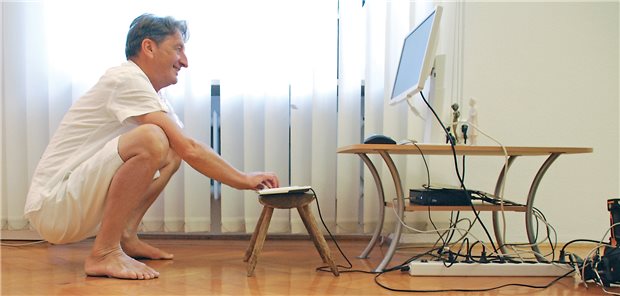 Dr. Martin Oswald in seiner Praxis: Stühle gibt es in seinen Behandlungsräumen nicht. Am Computer arbeitet er in der Hocke.