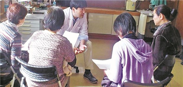 Dr. Masaharu Tsubokura (M.) klärt im Frühjahr 2011 nach der Atomhavarie von Fukushima an einer Klinik in Minamisoma Einwohner über die Modalitäten des Screenings auf Strahlenexposition auf.