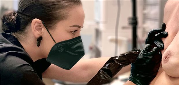 Nahaufnahme von Dr. Precht, die eine Brustwarze tätowiert.