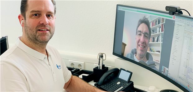 Hausarzt zur Praxis-IT: „Terminvergabe? Das kann der Computer besser“ Dr. Stefan Spieren im Praxisshirt vor Bildschirm und Kamera; auf dem Bildschirm ist ein Mann zu sehen,