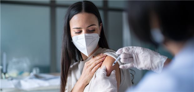 Drittimpfung beflügelt Aktienkurse von Corona-Vakzin-Produzenten Frau mit FFP2-Maske wird geimpft.