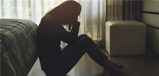 Erstmals seit acht Jahren wieder mehr Suizide Frau sitzt im halbdunklen auf dem Boden und hält die Hände vor das Gesicht.