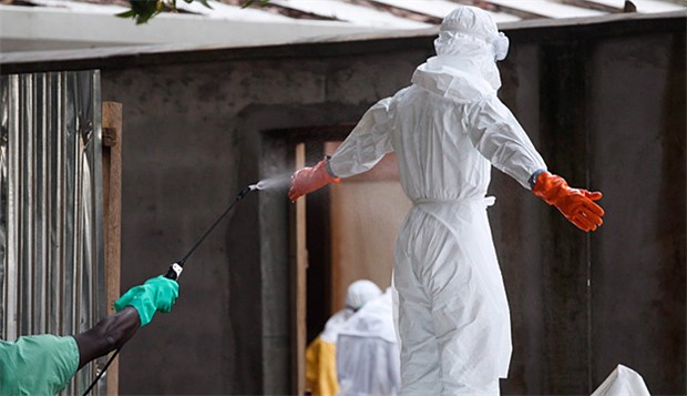 US-Arzt geht es besser - experimentelle Therapien Ebola-Vorsichtsmaßnahme in Liberia: Eine Krankenschwester in Schutzkleidung wird mit Desinfektionsmittel besprüht.