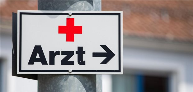 Ein Schild mit der Aufschrift „Arzt“ hängt an einer Straßenlaterne.