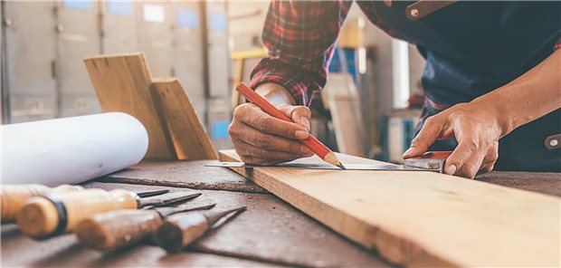 Ein Tischler bei der Arbeit mit einem Holzbrett. 