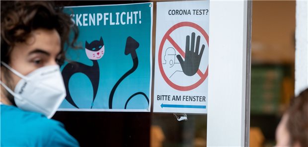 Ein Arzthelfer informiert Patienten in einer langen Schlange vor einer Arztpraxis im Bezirk Neukölln über den Corona-Test. Die Praxen sind in der Pandemie eine große Stütze des Gesundheitswesens. Davon sind viele Experten überzeugt. (Archivbild)