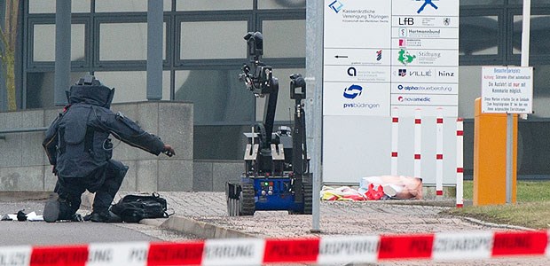 Bombenalarm bei der KV Thüringen Ein Beamter des Kommandos für Unkonventionelle Spreng- und Brandvorrichtungen kniet nach der Sprengung eines Rucksacks und einer Kiste neben einem Roboter.