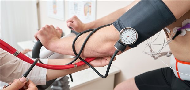 Eine männlicher Patient, der auf einem Fahrradergometer in die Pedale tritt, führt einen Belastungstest durch, um die Herzfunktion zu überprüfen.
