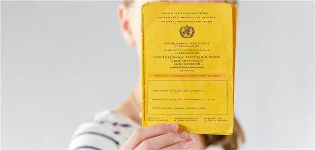 Eine junge Frau hält ihren Impfpass in die Kamera.