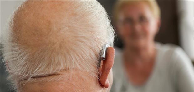 Mann mit Hörgerät spricht mit einer Frau.