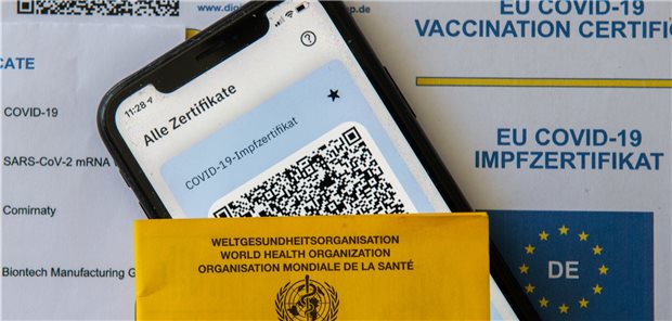 Apotheken starten mit digitalem Corona-Impfnachweis – Praxen müssen warten Ein Impfpass und ein Smartphone, auf dem die App CovPass läuft, liegen auf einem Impfzertifikat, das von einer Apotheke ausgestellt wurde.