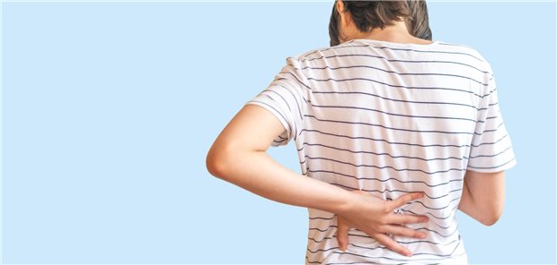 Kindliche Rückenschmerzen: Eine neue Volkskrankheit? Ein Jugendlicher hält sich den Rücken.