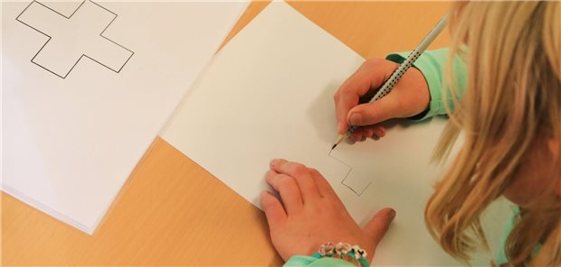 Kind zeichnet ein Kreuz.