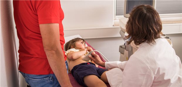 Ein Kinderarzt untersucht ein Kind mittels Ultraschall. Die Pädiater warnen vor Leistungskürzungen, sollte die mit dem TSVG eingeführte Zusatzvergütung für mehr Termine wieder gestrichen werden.&#xA;