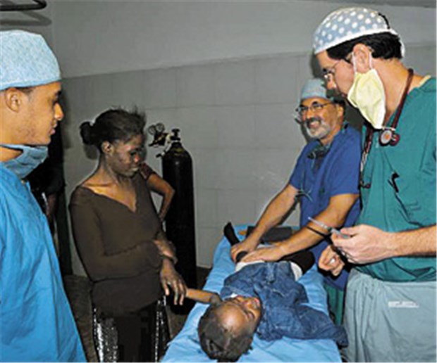 Haiti: "Ich bin gerettet, ruft das kleine Mädchen, ich bin gerettet" Ein Lächeln, weil es dem kleinen Patienten gut geht: Dr. Eckehart Wolff (2. von rechts) mit einem Operationsteam im Einsatz in Port au Prince. © Deutsche Missionsgemeinschaft (2)