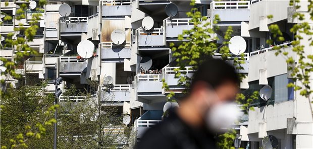Bürger aus Sozialbrennpunkten priorisiert impfen? Ein Mann geht mit Schutzmaske im Stadtteil Chorweiler an einem Hochhaus vorbei. Die Stadt Köln will in Stadtteilen mit hoher Inzidenz bevorzugt impfen.