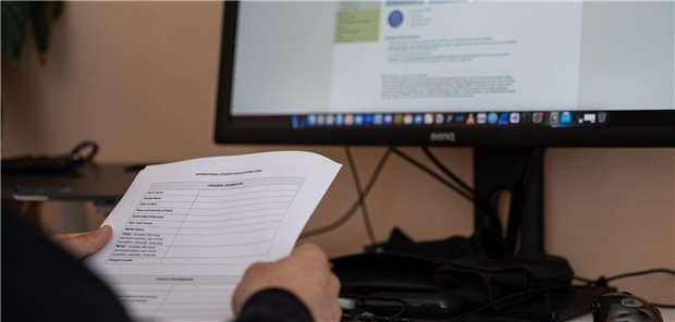 Ein Mann sitzt mit Bewerbungsunterlagen für ein Studium im Ausland an einem Schreibtisch. Viele Medizininteressierte schalten dafür auch Vermittlungsagenturen ein.