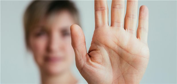 Frau zeigt ihre Handfläche um das Sigmal "Stopp" zu geben