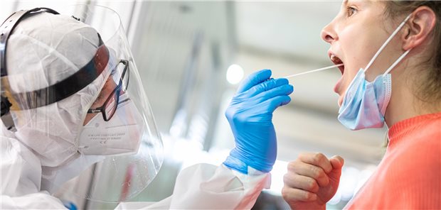 Ein Mitarbeiter der Johanniter-Unfall-Hilfe nimmt einen Abstrich von einer Reiserückkehrerin im Corona-Testzentrum am Flughafen Hannover-Langenhagen. Reiserückkehrer dürfen auch in Praxen gehen, um dort den Test vornehmen zu lassen.