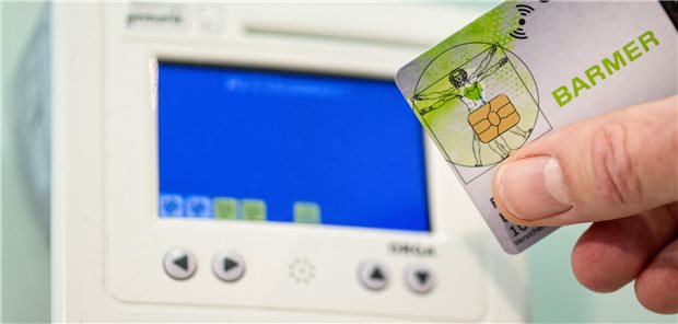 E-Rezept: Störung behoben, Probleme noch längst nicht alle gelöst Ein Mitarbeiter einer Apotheke steckt eine Gesundheitskarte in ein Lesegerät.