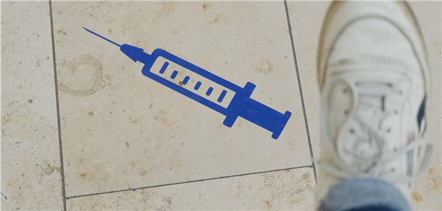 Neue STIKO-Empfehlung: Vormals SARS-CoV-2-Infizierte erstmal nicht impfen Symbol einer Spritze ist auf dem Boden der Muldentalhalle in Halle, die ab Mitte März als Impfzentrum fungiert.